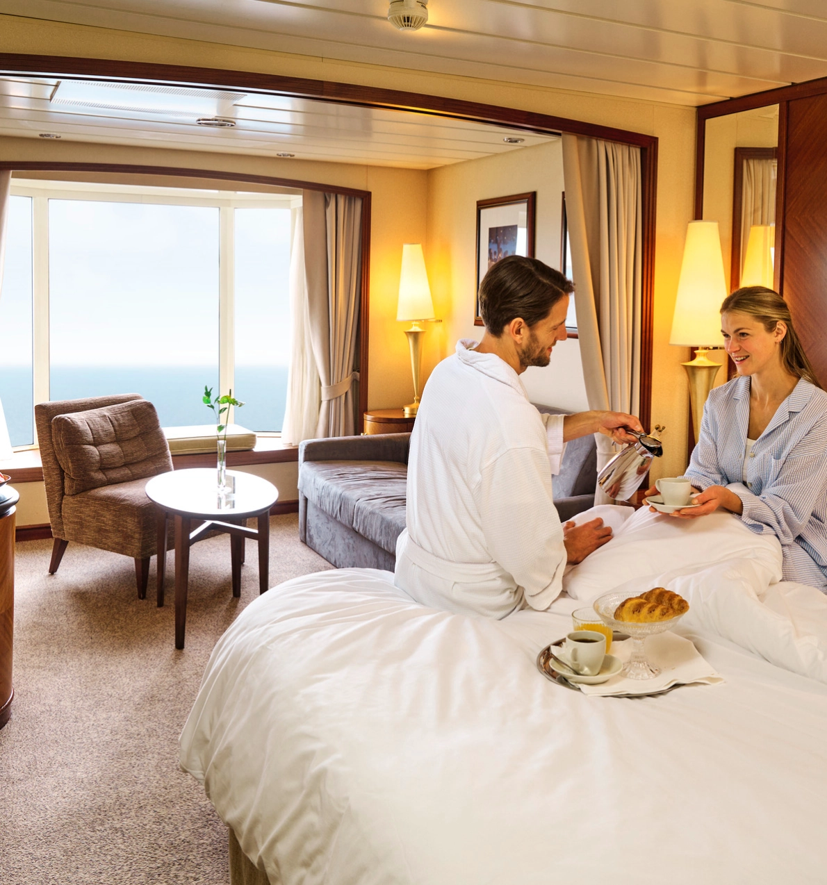 Par som drikker kafe i sengen i en suite