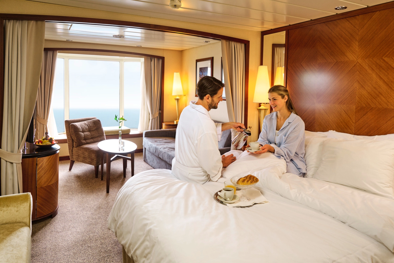 Par som drikker kafe i sengen i en suite