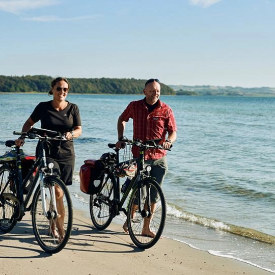 Par med sykkel på stranden.jpg